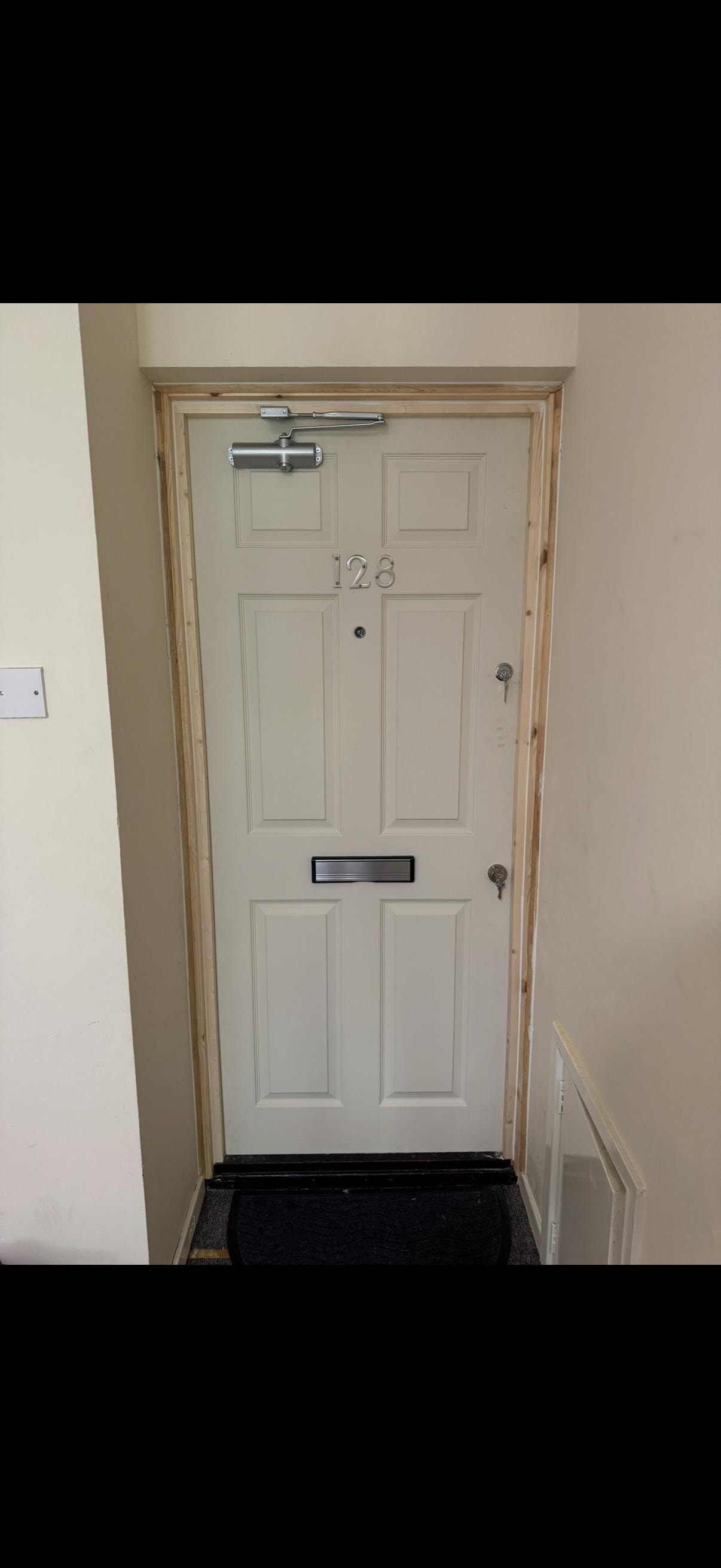 Cream panelled apartment fire door number 128
