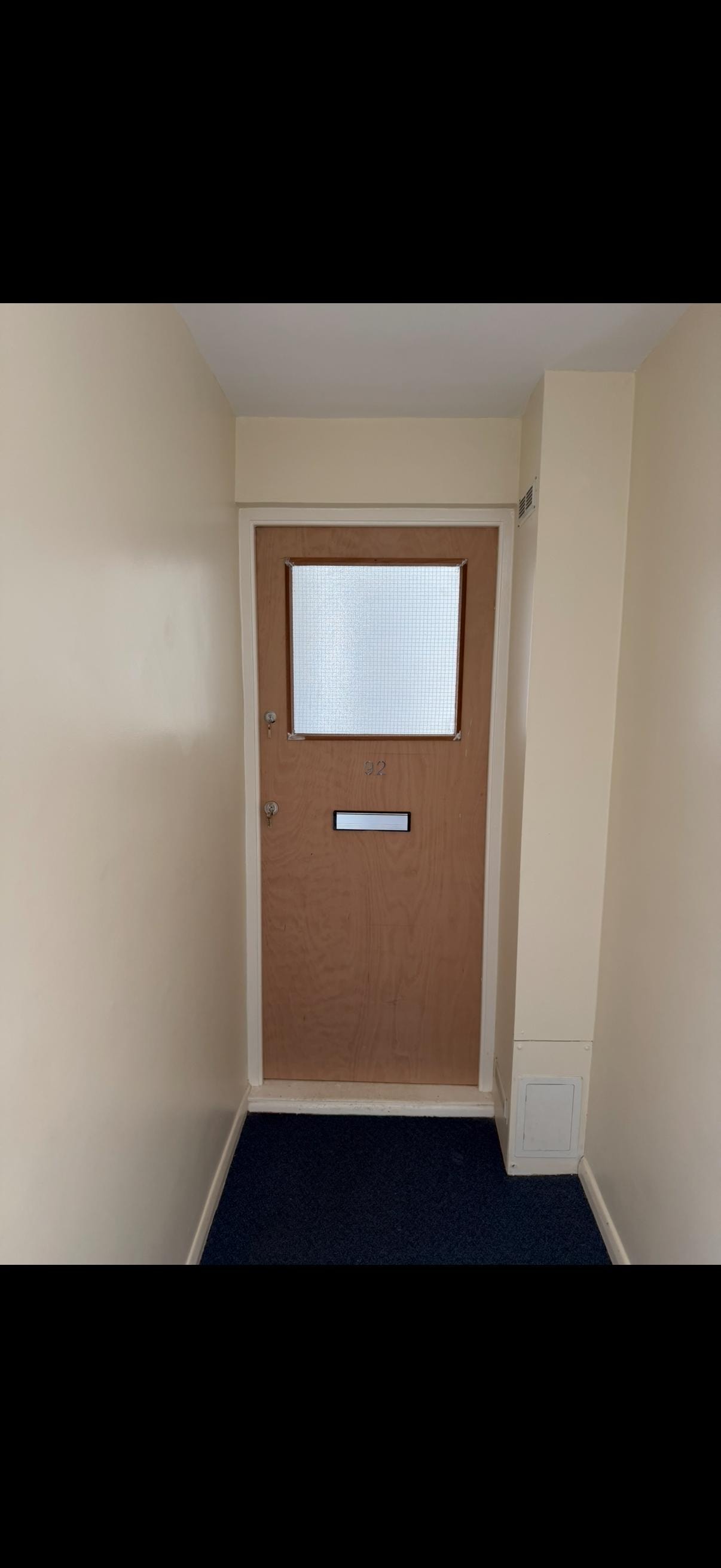 Narrow hallway with wooden glazed fire door